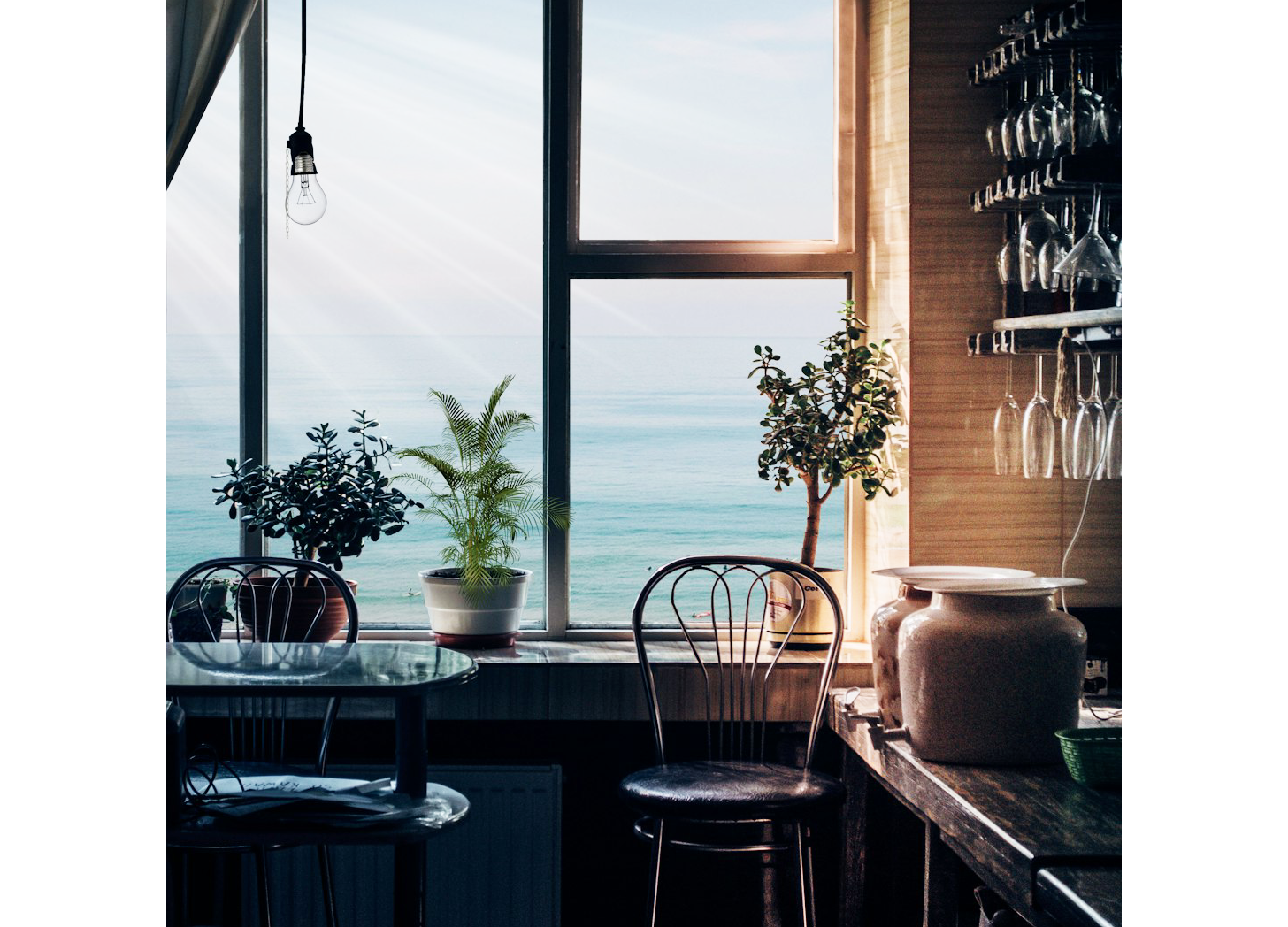 A lone chair faces an open window toward the vast blue ocean, inviting reflection and calm.