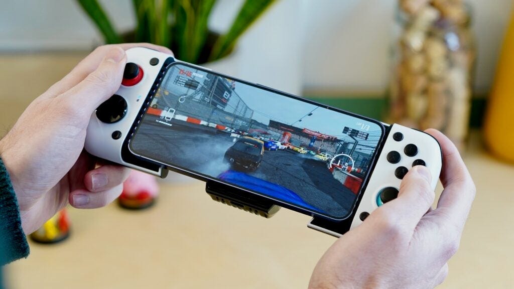 Hands holding GameSir X3 controller attached to smartphone with racing game.