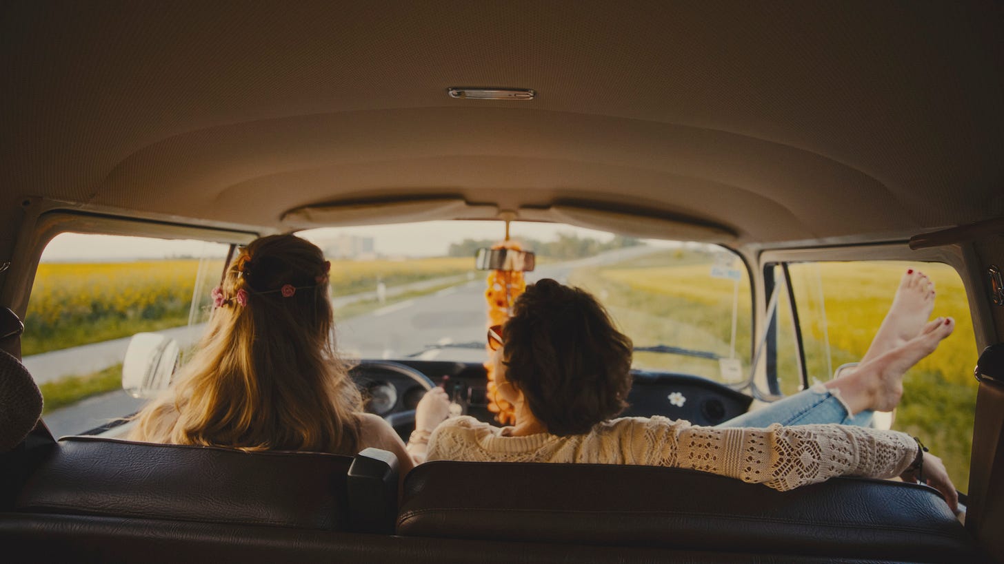 Two women driving on a open highway, view from behind front seats