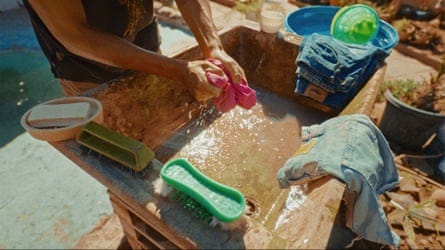 A person washes clothes in a stone basin outside