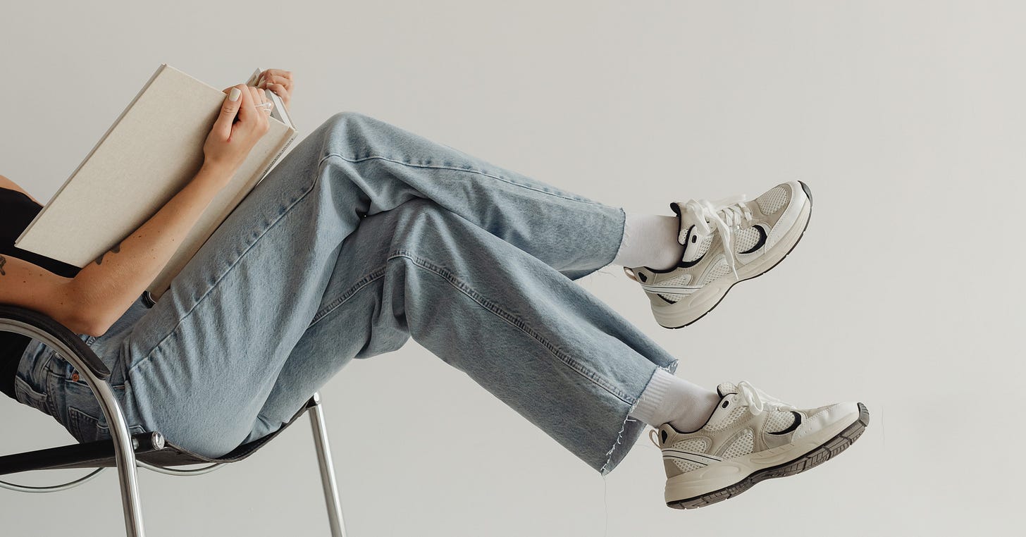 TBR Writes: A woman leans back into a chair and reads a giant book