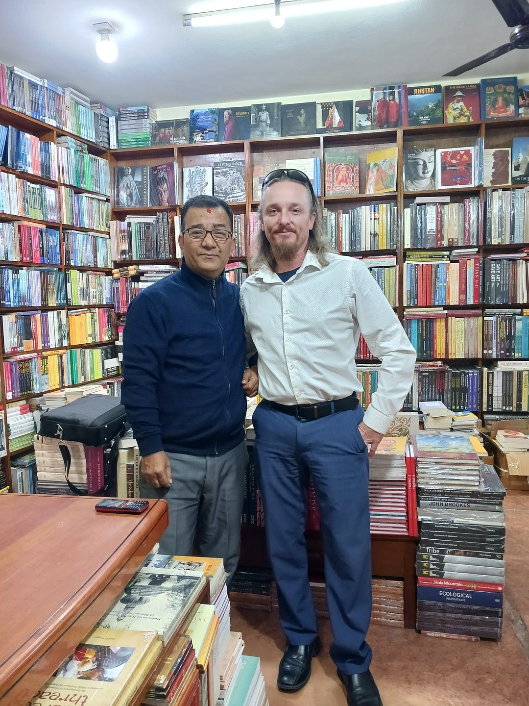 On the left stands Bidur Dangol. On the right, your author. In the background are stuffed bookshelves inside of Vajra Bookstore.