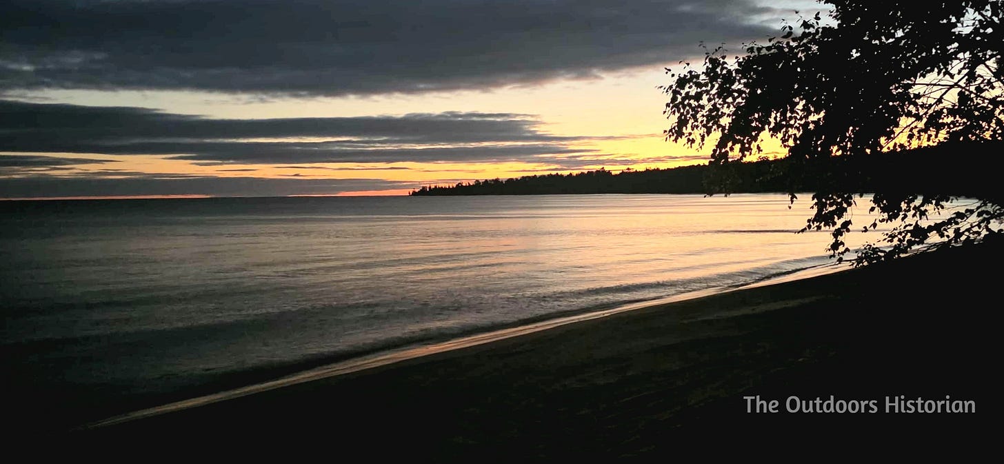 A calm Lake Superior under the golden glow of a sunset.