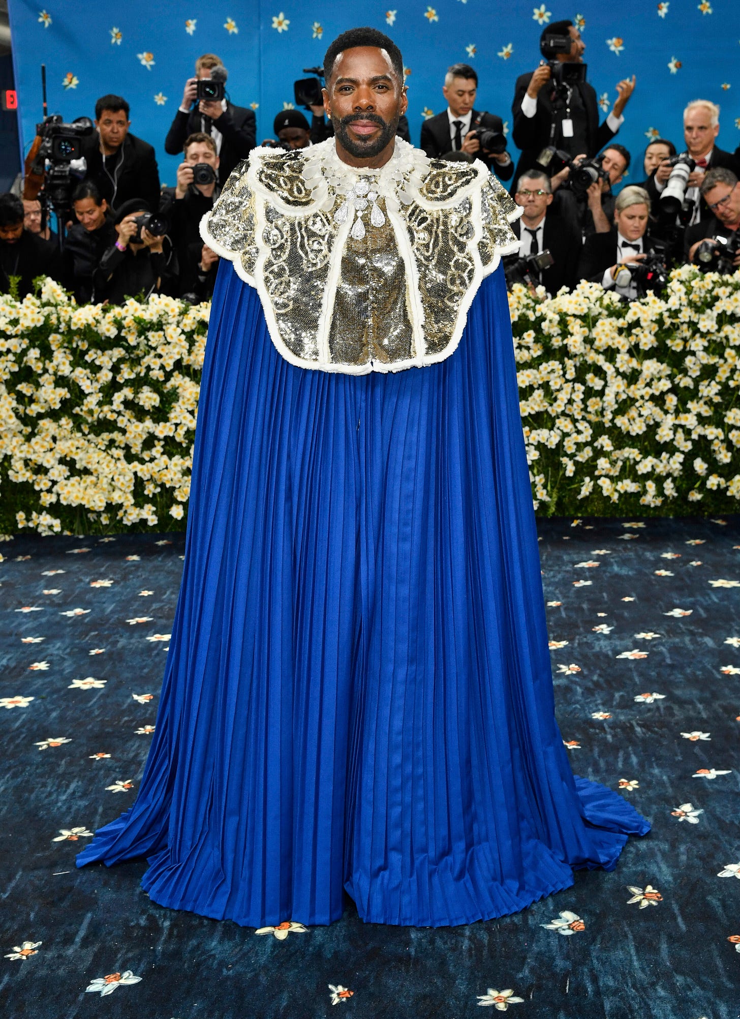 Colman Domingo wearing a floor-length pleated blue cape with silver shoulder detailing 