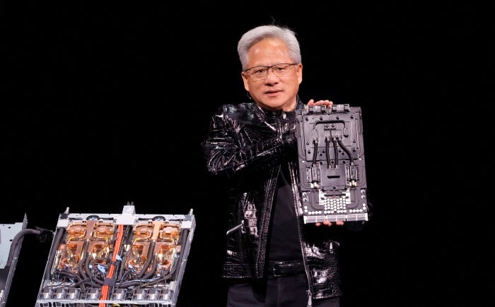 Nvidia CEO Jensen Huang holding a computer component while standing on stage during a keynote address.