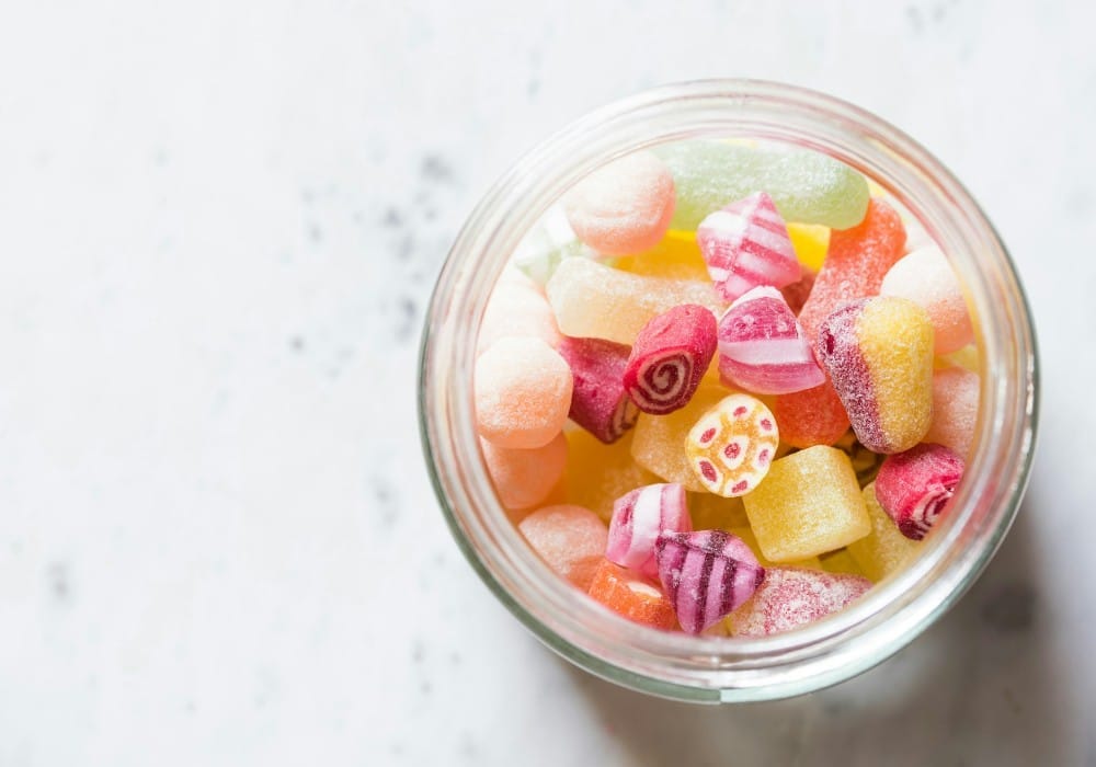 Top down view of colorful candy in a glass jar on white marble countertop Top down view of colorful candy in a glass jar on white marble countertop