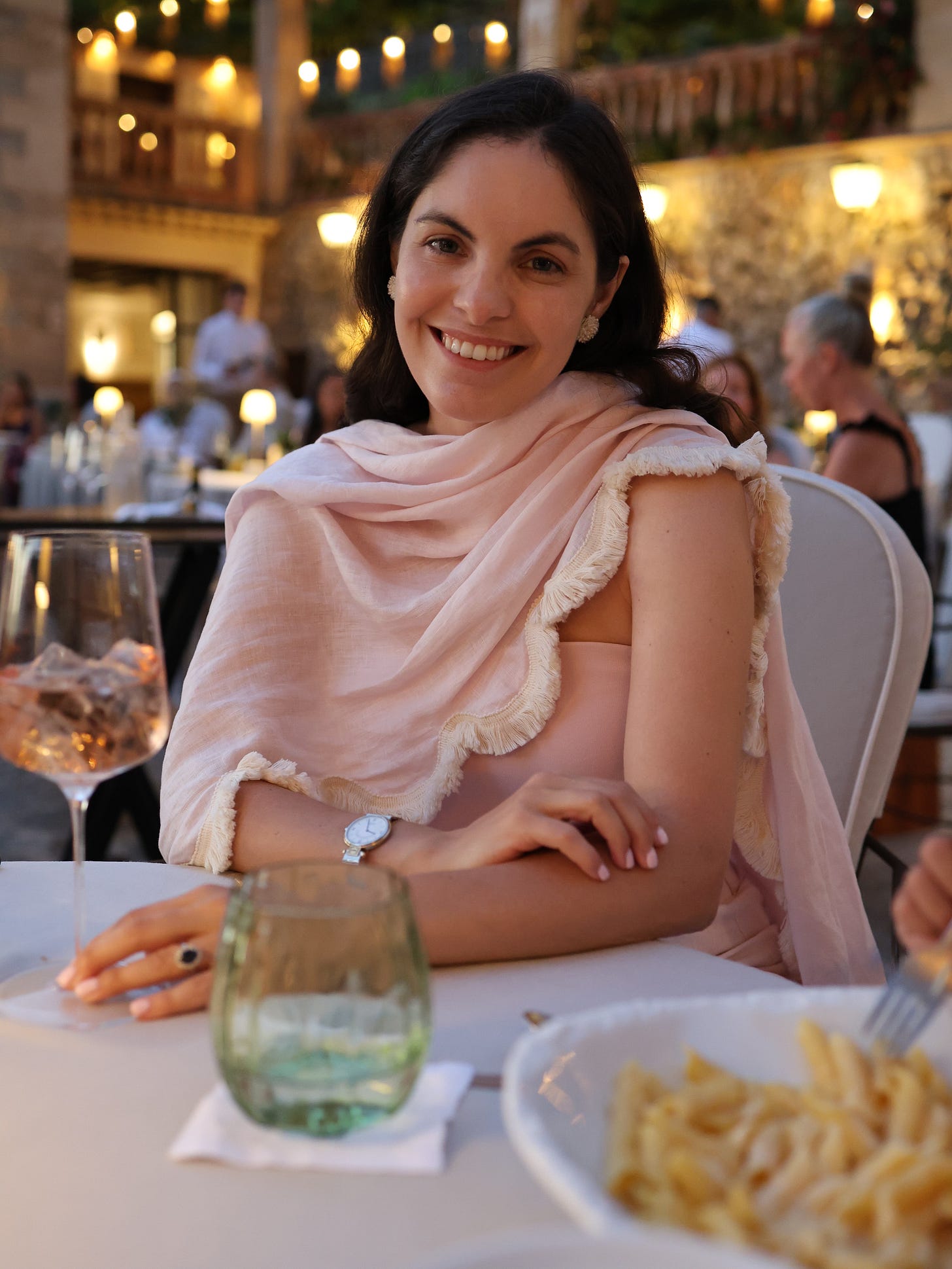 A woman in a pink fringed wrap smiling at a candlelit dinner table at El Olivo, La Residencia A woman in a pink fringed wrap smiling at a candlelit dinner table at El Olivo, La Residencia