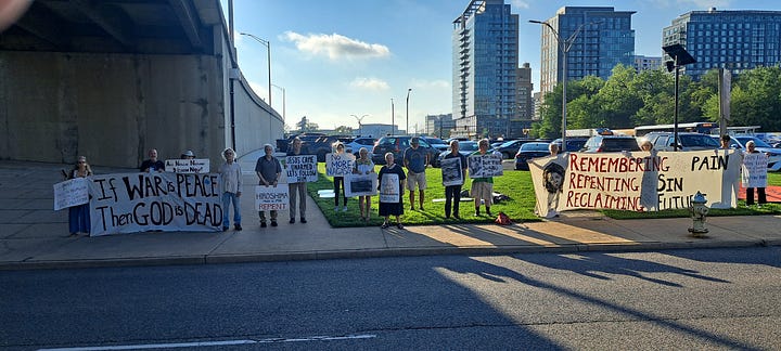 protesters stand on the side of the freeway holding signs commemorating the anniversary of the bombings. 