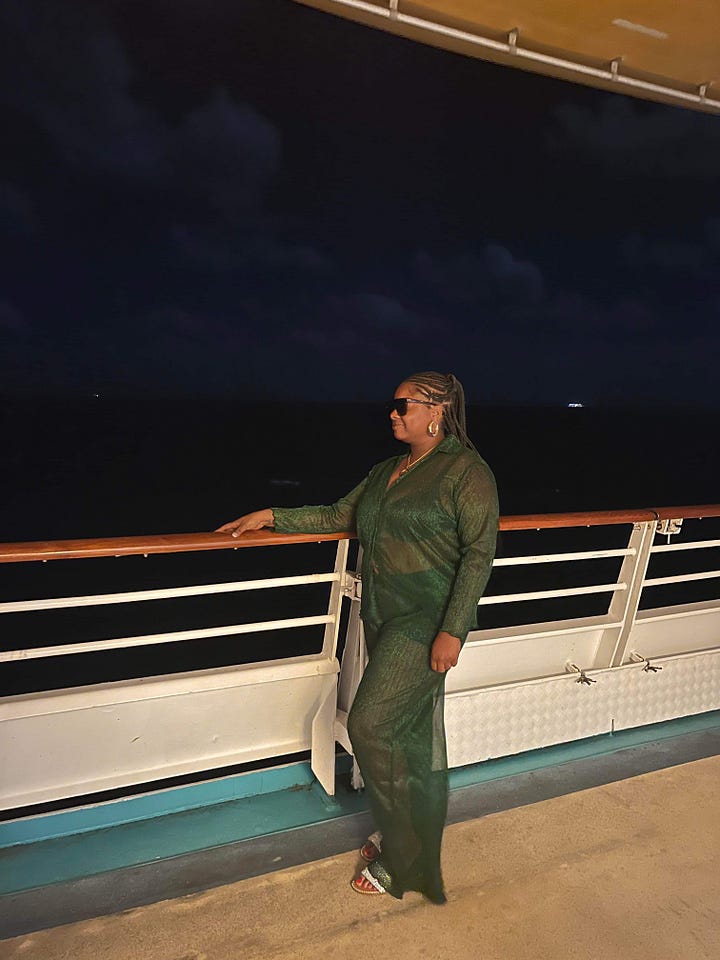 Left to right: Black women similing in the hallway near an elevator dressed in a blue silk outfit. Black women standing a hallway near an elevator on a cruise ship dressed in a brown matching outfit. Black woman admires the sea at night on a cruise ship dressed in a green sheet matching pants set. Black woman poses on a stair case in orange matching set.
