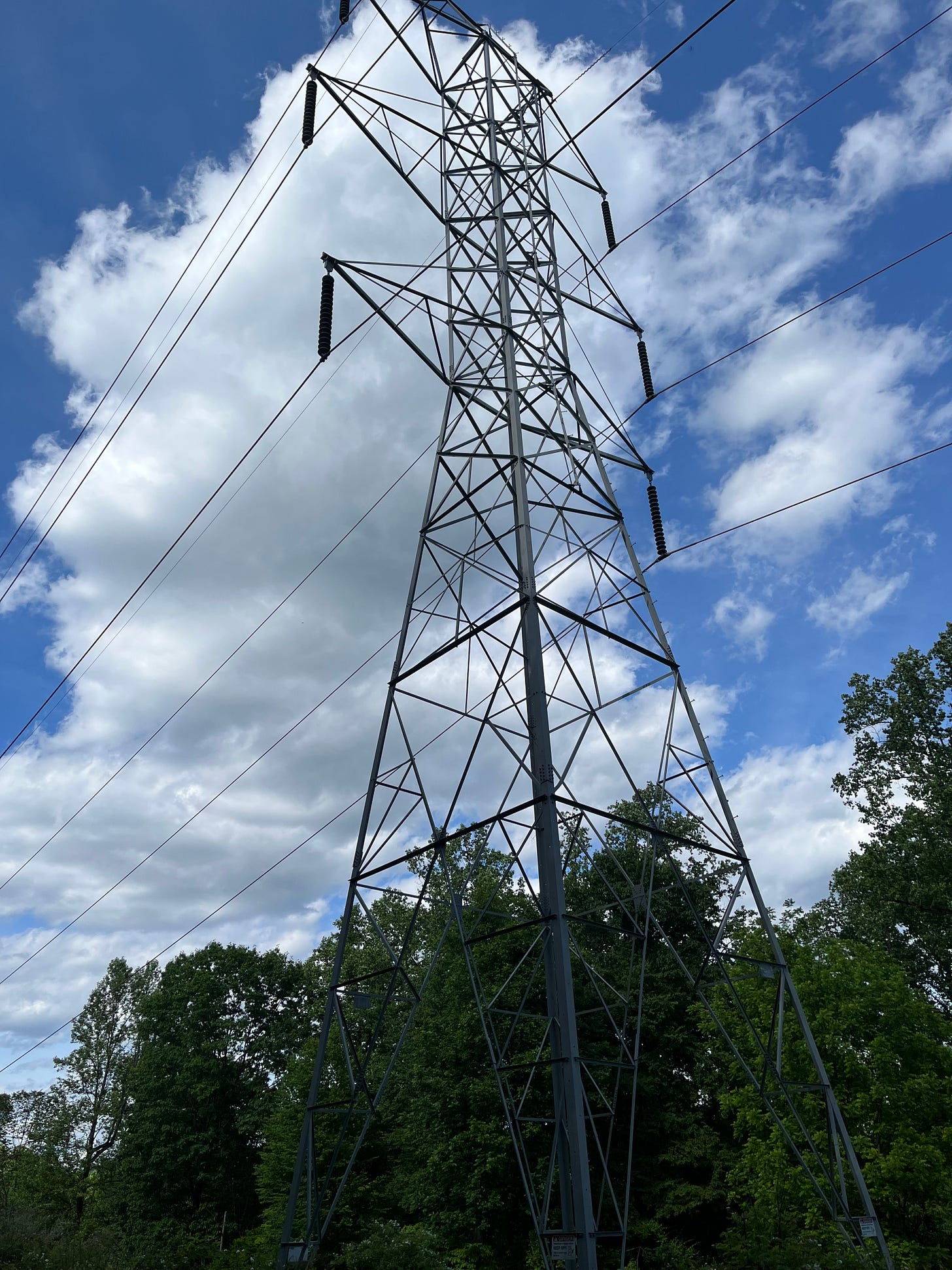 Photo of high tension power lines against a blue sky with white clouds.