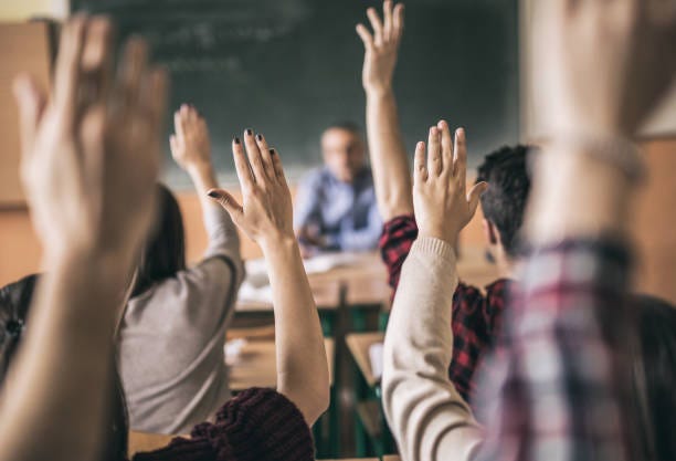 We all know the answer! Rear view of group of students raising hands to answer teacher's question in the classroom. Focus is on hands in the middle. hands raised in classroom stock pictures, royalty-free photos & images We all know the answer! Rear view of group of students raising hands to answer teacher's question in the classroom. Focus is on hands in the middle. hands raised in classroom stock pictures, royalty-free photos & images