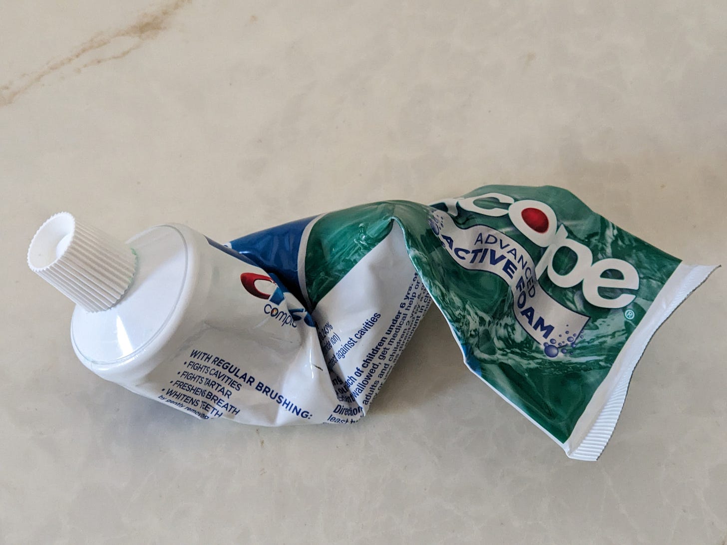 A tube of Crest toothpaste. It has been twisted and mangled. It looks sad.