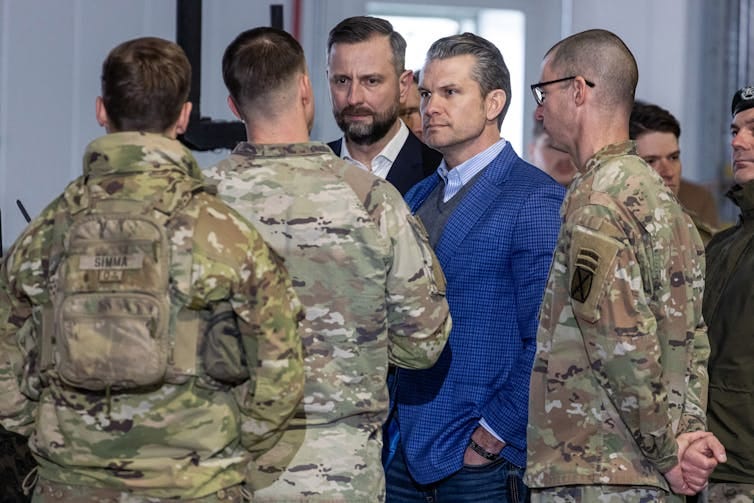 Two men in suits talk with three men in army camouflage uniforms. Two men in suits talk with three men in army camouflage uniforms.