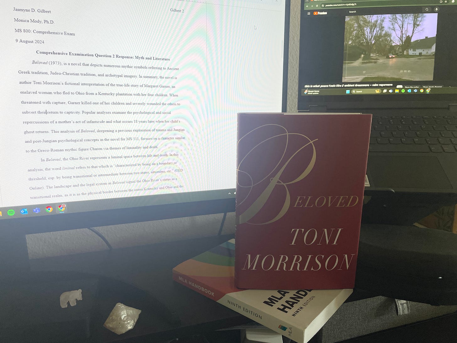 A grainy image of the author's copy of Beloved with a red cover and gold lettering. Taken in front of dual computer monitors. A grainy image of the author's copy of Beloved with a red cover and gold lettering. Taken in front of dual computer monitors.