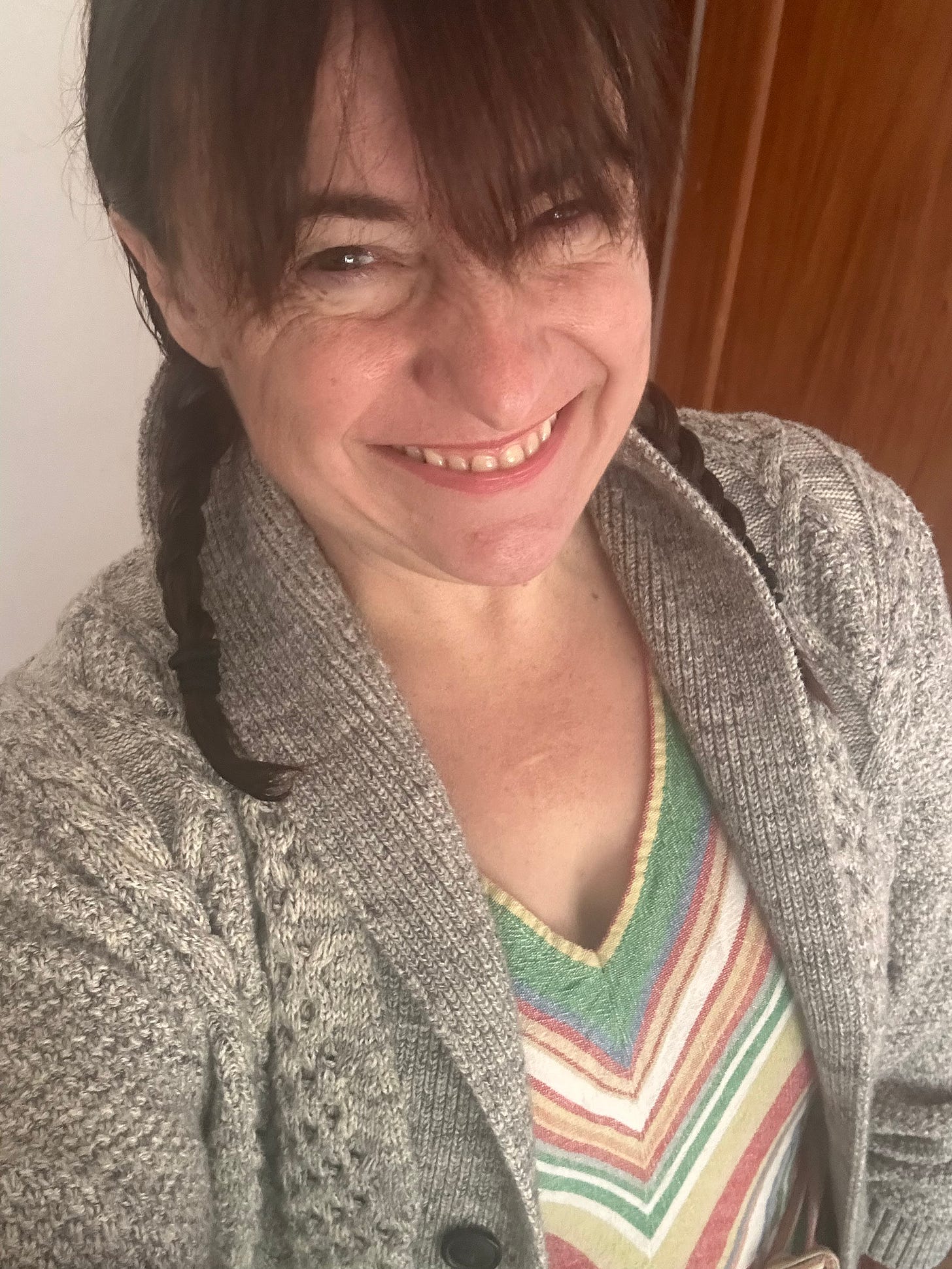 writer-artist Kathryn Vercillo on her 46th birthday wearing a neutral knit cardigan and a colorful striped dress