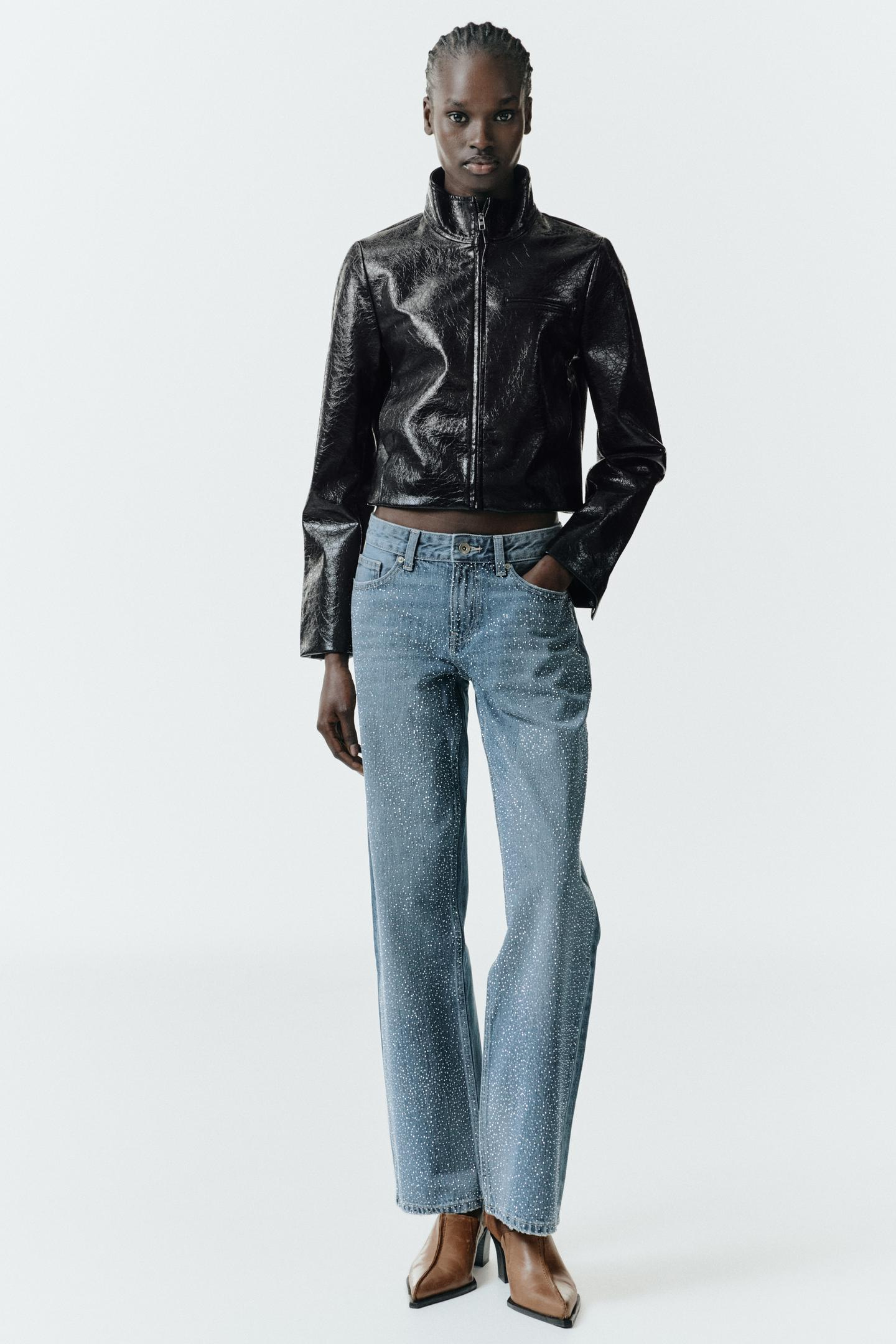 Black zip-up jacket and blue glitter jeans outfit, front pockets, brown high-heeled shoes.