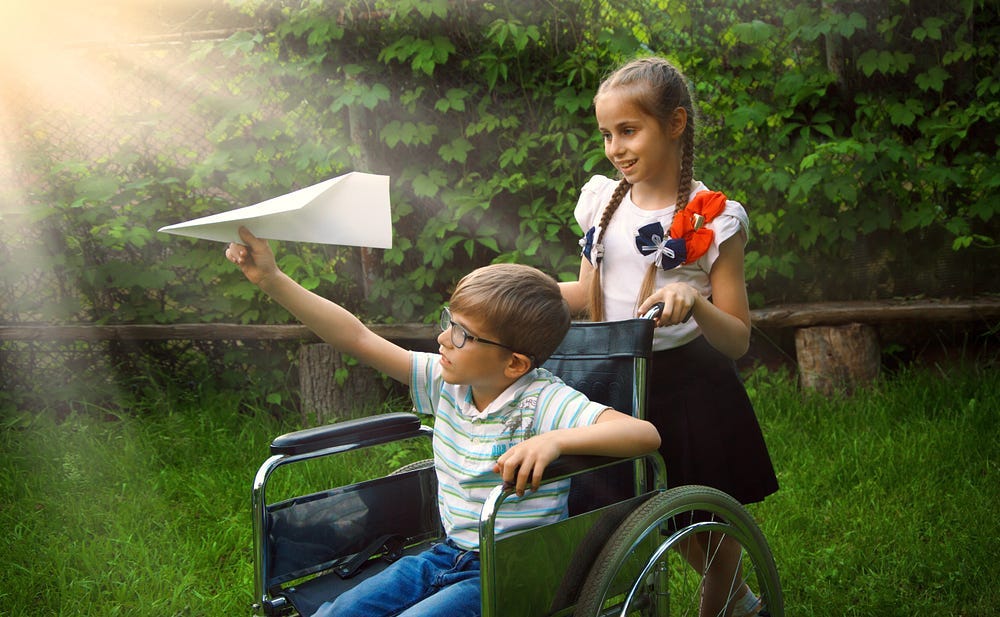 Girl with flowered blouse pushing a young boy in wheelchair, he is about to throw a paper airplane. Girl with flowered blouse pushing a young boy in wheelchair, he is about to throw a paper airplane.