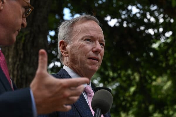 Eric Schmidt, Google’s former C.E.O., is seen in profile with a microphone pointed at him.