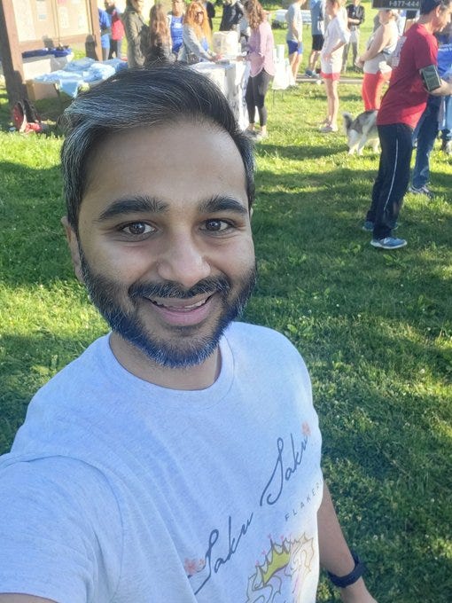 Selfie of Sauleh wearing a T shirt from SakuSaku Flakerie, best bakery ever. It's a sunny day and he's standing on green grass with a crowd in the background. 