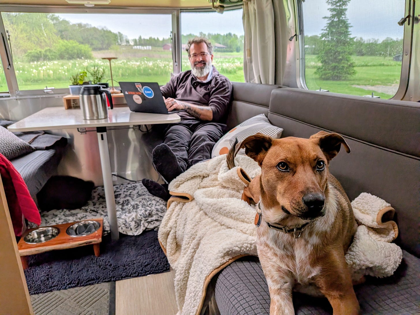 The author sitting in his Airstream with his Macbook and a pot of coffee and his dog Frank as he's writing this unfiltered essay.