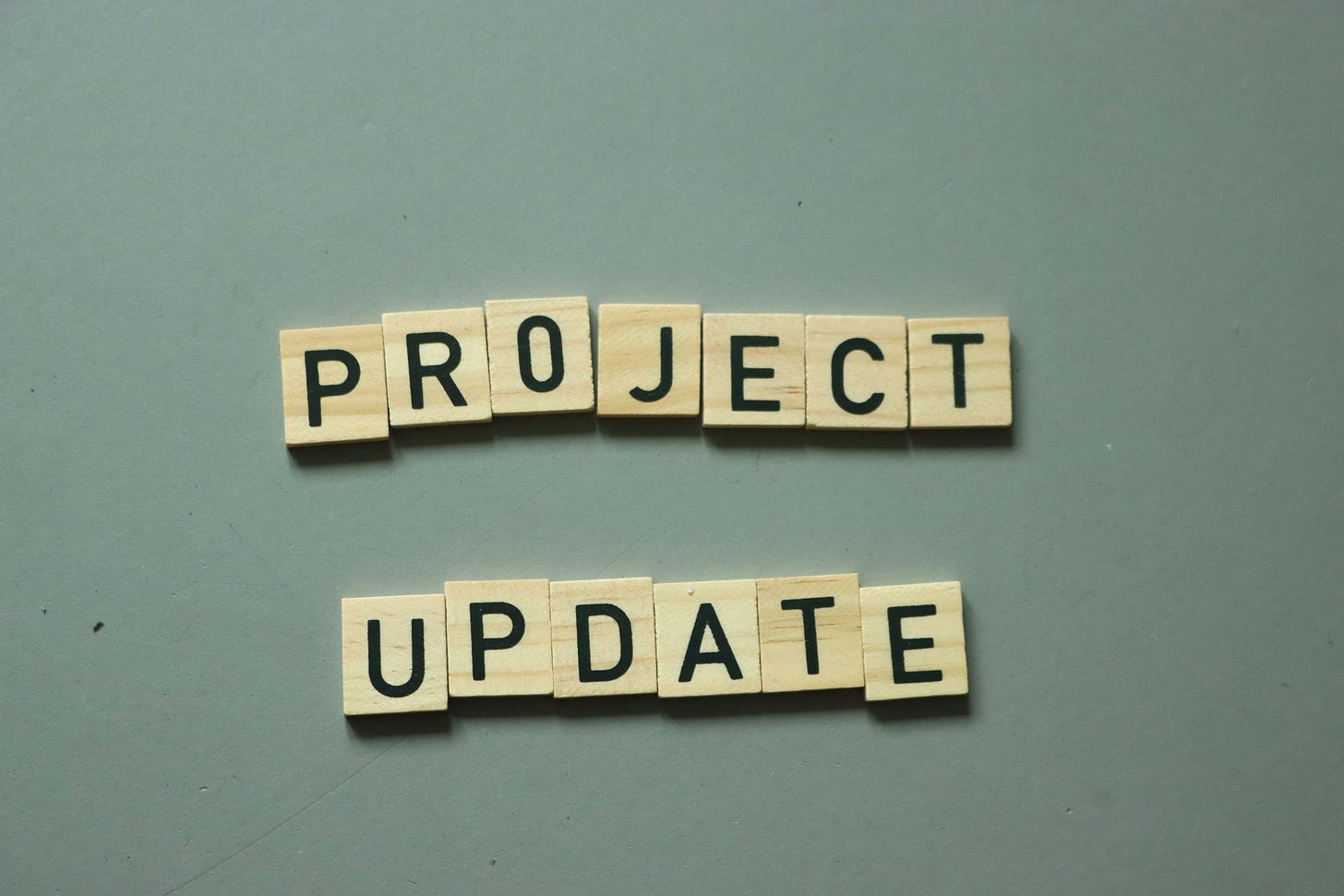 A grey background with small wooden tiles with a letter on each, that spells out Project Update A grey background with small wooden tiles with a letter on each, that spells out Project Update