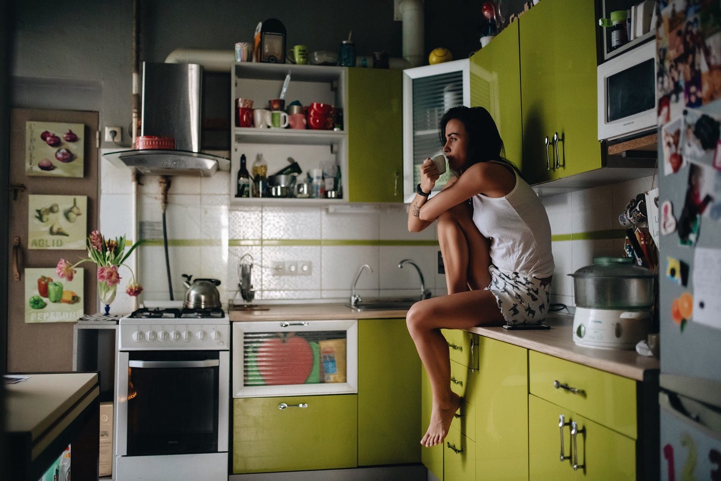 A woman sits on a kitchen counter and stares into space as she drinks espresso. A woman sits on a kitchen counter and stares into space as she drinks espresso.