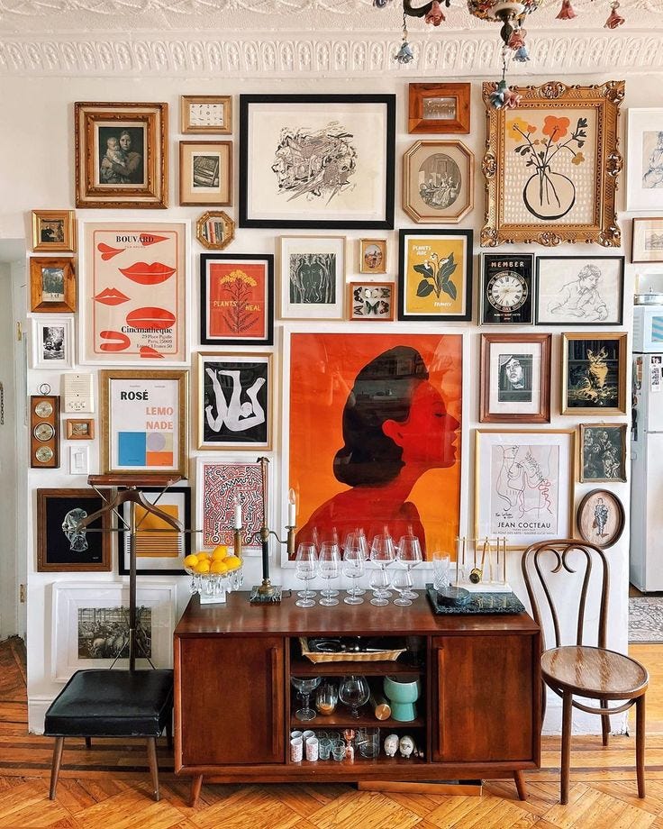 This may contain: a room filled with lots of framed pictures and art on the wall next to a wooden table This may contain: a room filled with lots of framed pictures and art on the wall next to a wooden table