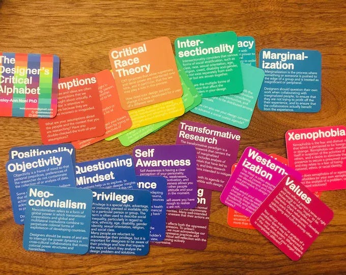 A set of colorful cards laid out on a wooden table, each labeled with concepts such as Critical Race Theory, Intersectionality, Marginalization, Xenophobia, Privilege, and Neo-Colonialism.