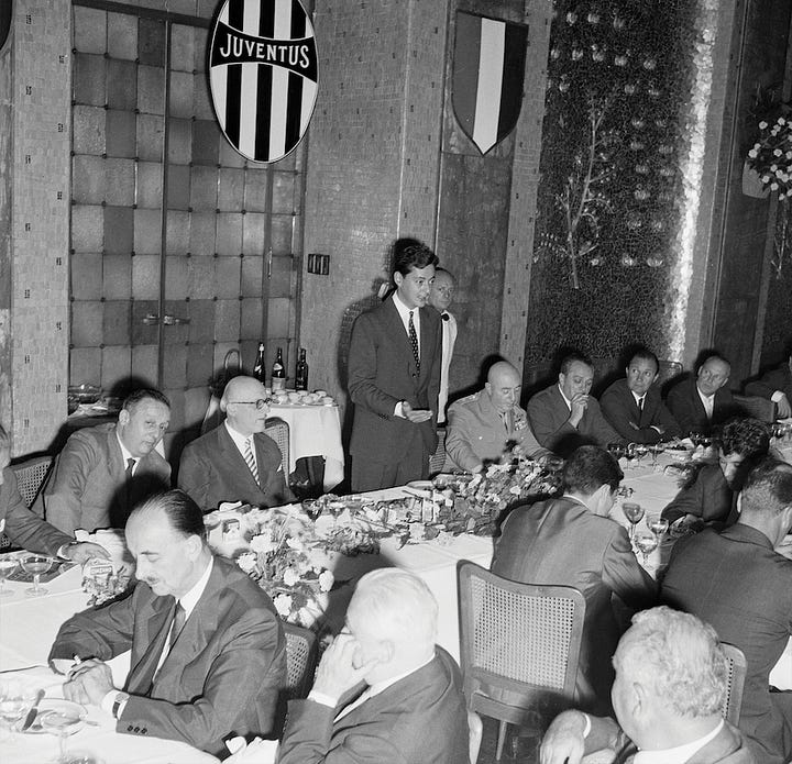 Umberto Agnelli with Juventus officials at a 1950s banquet featuring club crests and commemorative presentations.