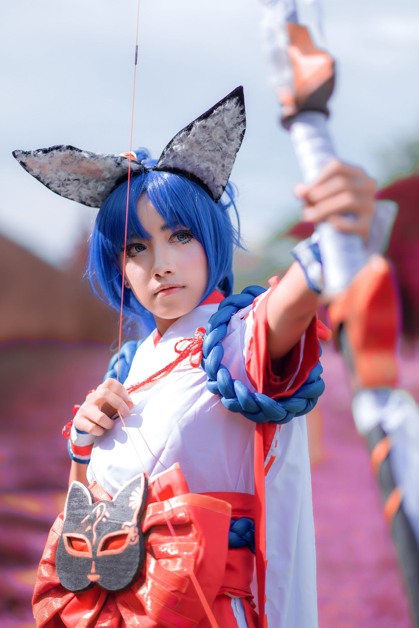 Youn girl in colorful garb and winged hat aiming an arrow into the sky