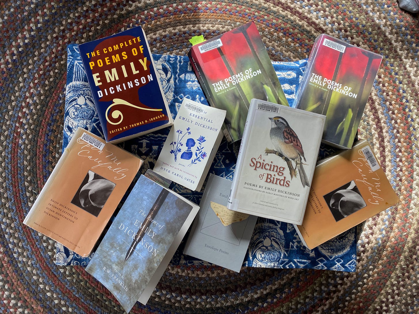 A large pile of different books by Emily Dickinson on a coffee table.
