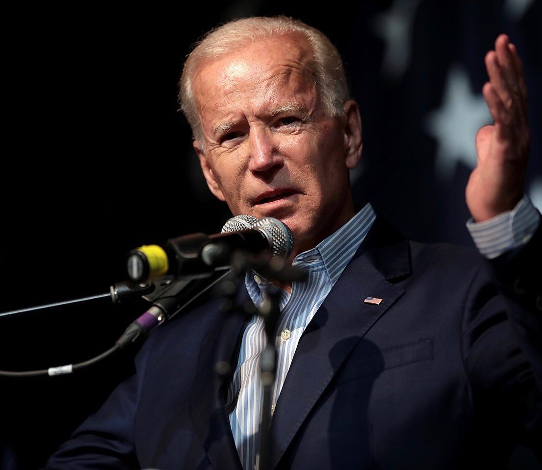 Joe Biden at a podium, with a serious expression and one hand raised to emphasize a point