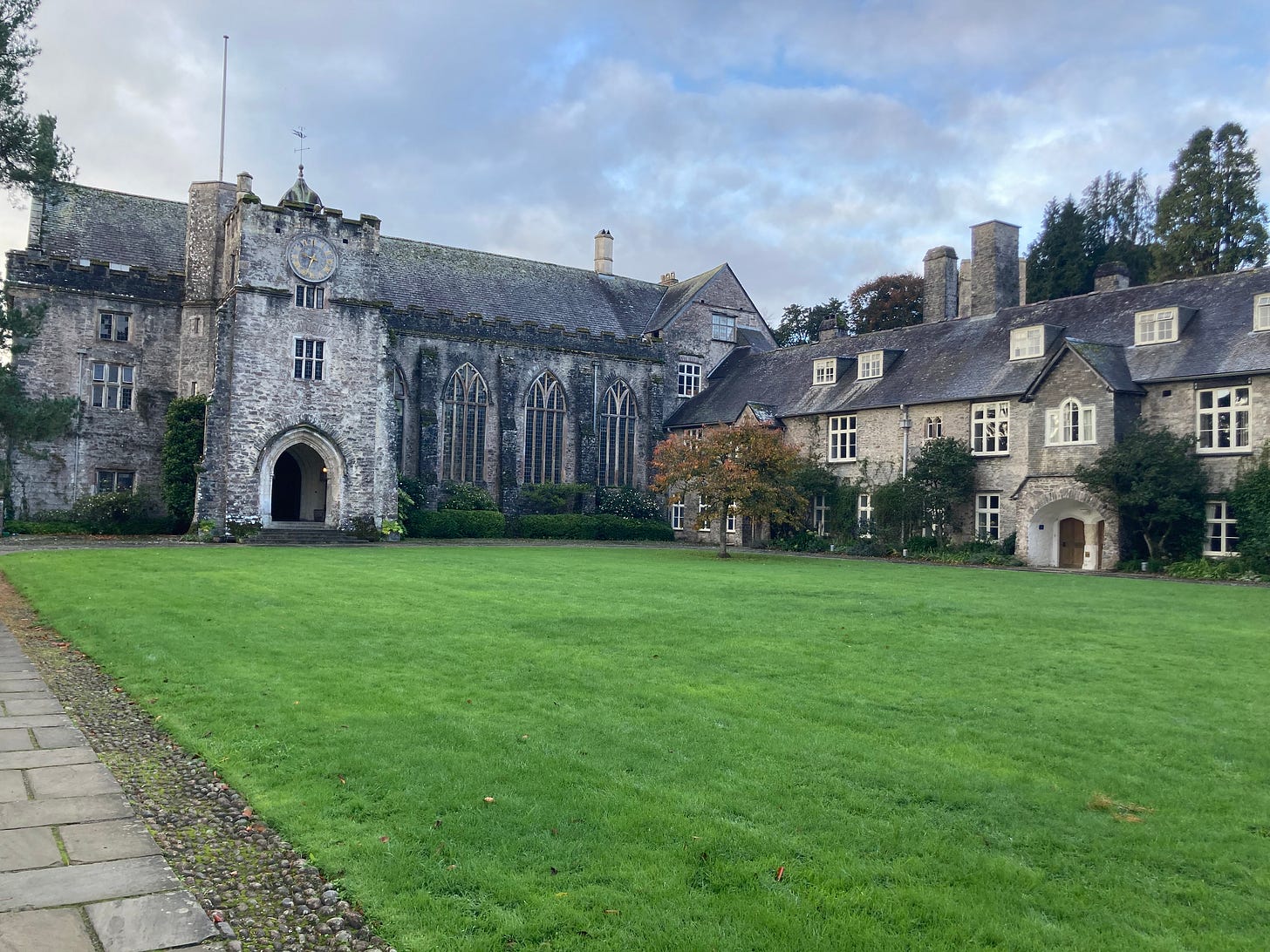 a medieval great hall with a green lawn in front