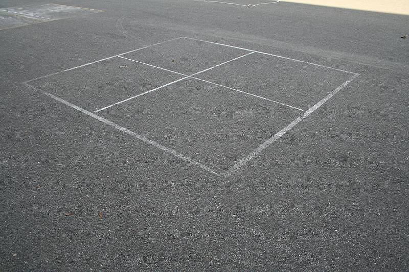 white four square court on dark asphalt