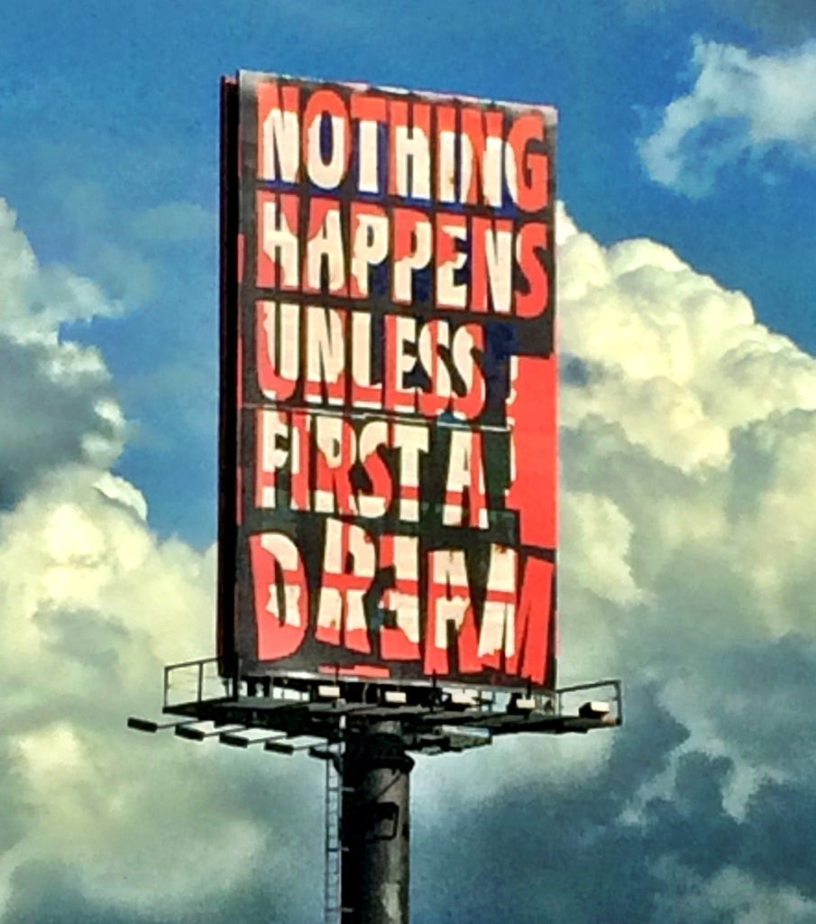 Billboard against the sky that says NOTHING HAPPENS UNLESS FIRST A DREAM