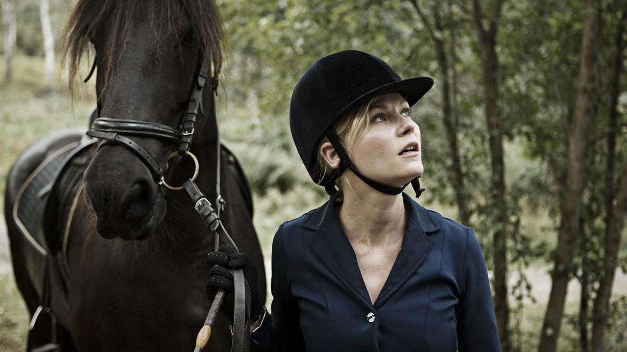 Film still from Melancholia. Justine leads her horse, looking at the sky.