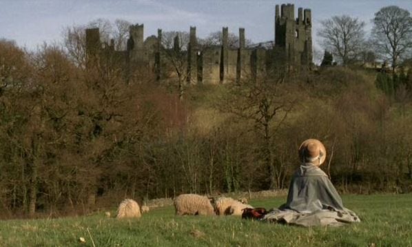 A woman looks at a burned-out manor