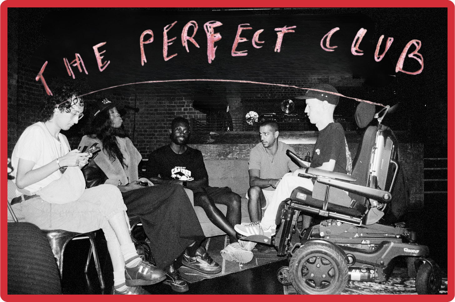 A black-and-white photo of five young people of different genders and ethnicities, sitting on sofas, chairs and in a wheelchair, in a large room with brick walls. The room looks fairly dark, with only limited artificial light. Above their heads, handwritten pink letters spell out "The Perfect Club."