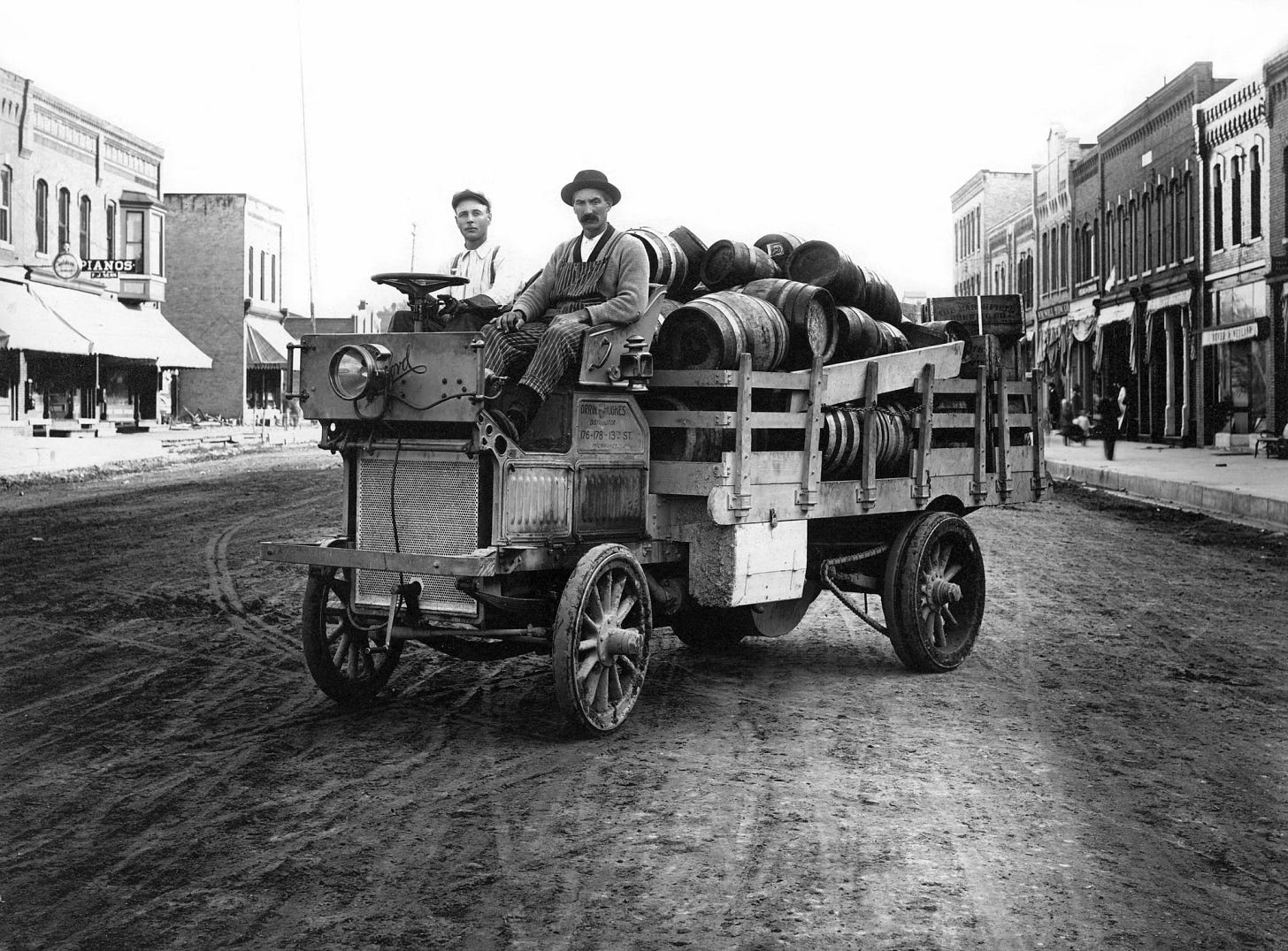 Early motor vehicle with a load of barrels on a turn-of-the-century street. Early motor vehicle with a load of barrels on a turn-of-the-century street.