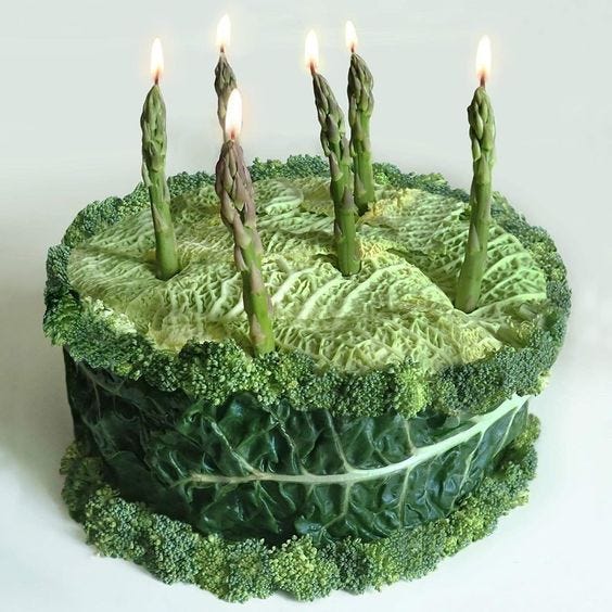 This may contain: a green cake with five lit candles on it's top surrounded by leafy greens This may contain: a green cake with five lit candles on it's top surrounded by leafy greens
