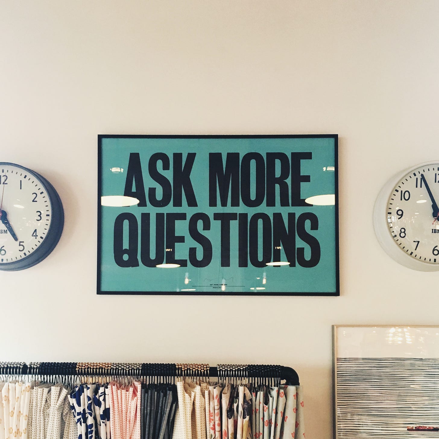 A poster on a wall which says Ask More Questions