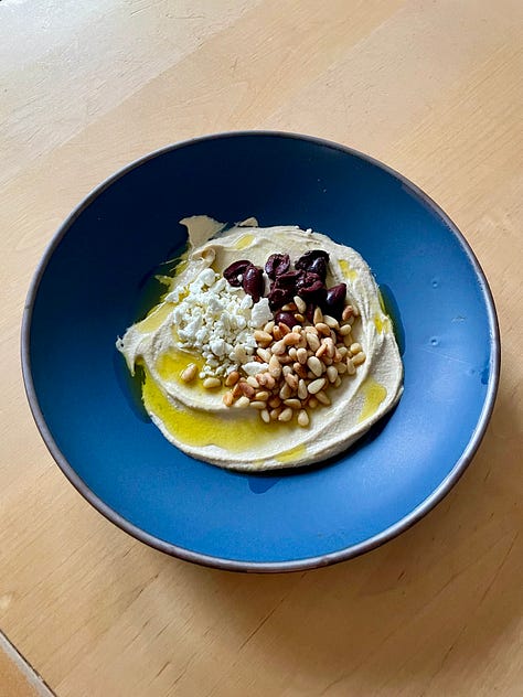 a blue bowl pictured with 3 different foods: salad, hummus, and pork tenderloin