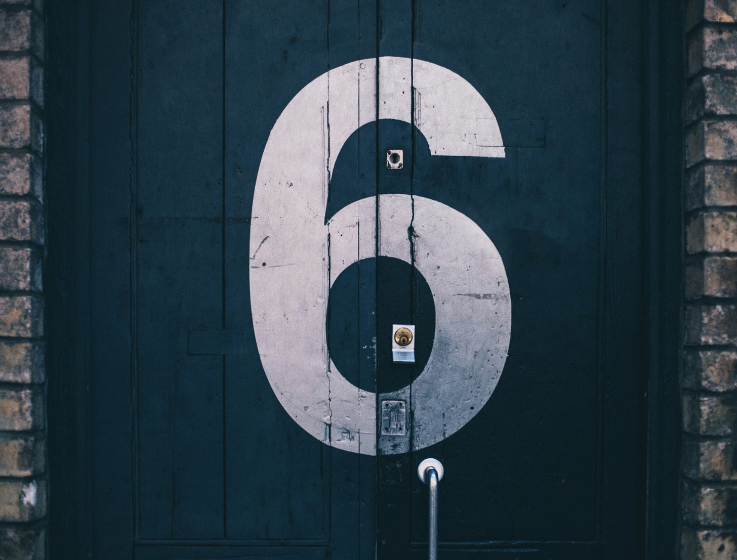 Number six painted in white on a black door.