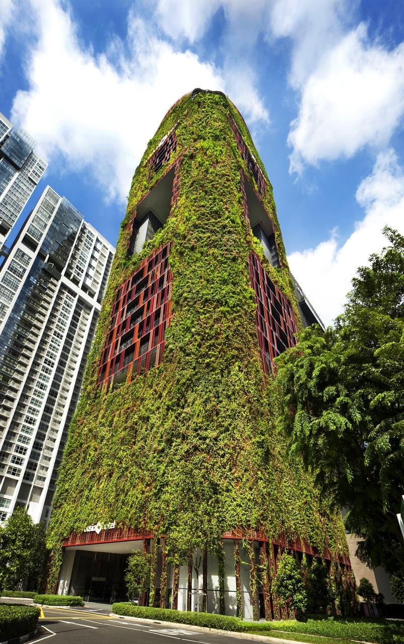The 27-storey Oasia Hotel Downtown features a plant-covered facade of red and green and outdoor communal spaces along its height.