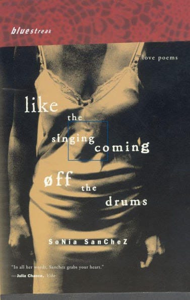 Pictured is a woman in sepia filter with just her body underneath a red diagonal trim at the top of the photo. The woman is in a cotton slip with her hands gently cupped at her sides. There are great shadows casted over her frame to the point one of her arms completely melts into the background while the title “Like the Singing Coming off the Drums” is written in white curly font across six different stanzas