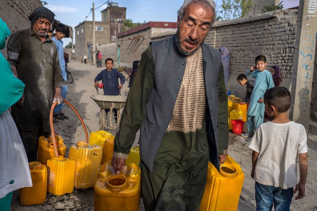 Neighbors gather to fill their drums with drinking water in Azara neighborhood in Kabul on June 14, 2023.