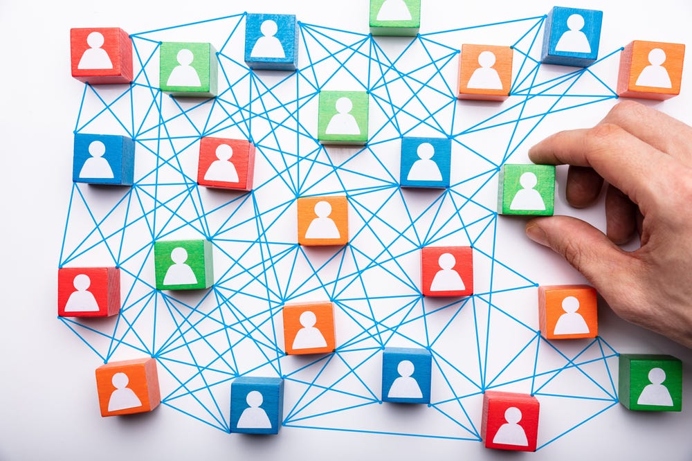 A hand holding a colorful block with people icons on it