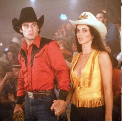 This may contain: a man and woman in cowboy hats standing next to each other with people watching them