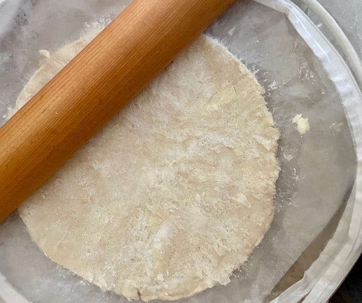 pastry cutter with pie crumbs and ice water/vinegar, and a rolling bag with rolling pin and pie crust