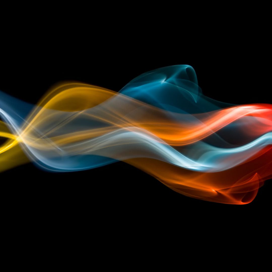 Energy flow flames in multi colours like yellow, blue and red against a black background.